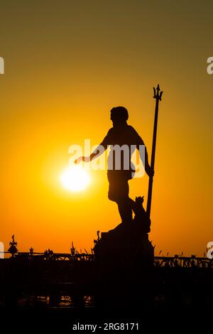 Die dunkle Silhouettenstatue des Neptun im Licht der untergehenden Sonne. Hel, Pommern, Polen Stockfoto