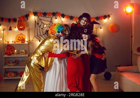 Eine Gruppe glücklicher lächelnder Freunde in verschiedenen originalen Halloween-Kostümen haben Spaß und Umarmungen. Stockfoto
