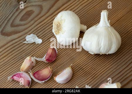 Stillleben von zwei Knoblauchköpfen und ein paar Knoblauchzehen auf Holzhintergrund. Horizontale Ansicht. Stockfoto