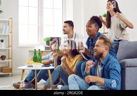 Eine Gruppe von Freunden, die auf dem Sofa sitzen und sich ein Spiel anschauen Stockfoto