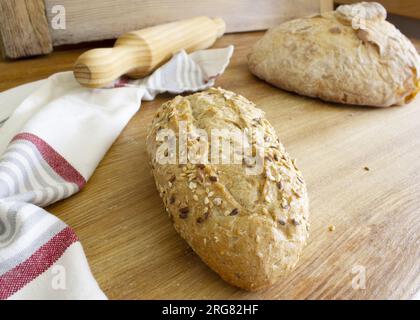 Köstliches und frisches Müsli-Brot im Vordergrund und traditionelles Brot und ein im Hintergrund auf dem Holztisch. Sesamsamen bedeckten es. H Stockfoto