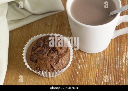 Köstliche Nahaufnahme des Muffins mit Schokoladenknuggets auf dem Holzhintergrund. Harmonische Farben. Makro und Draufsicht. Stockfoto