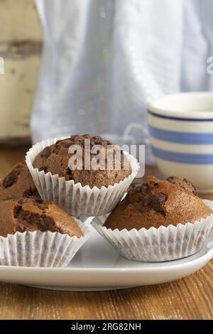 Nahaufnahme des köstlichen Stilllebens dunkler Schokoladen-Cupcakes, die zu Hause zubereitet werden. Gemütliche Atmosphäre. Muffins frisch gebacken. Vertikale Ansicht. Stockfoto