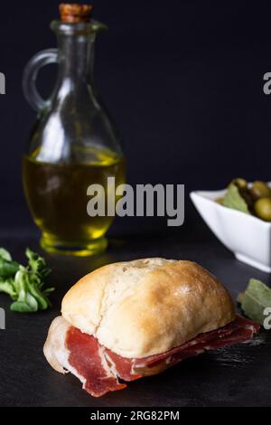 Aus nächster Nähe schmackhafte Muffins mit serrano-Schinken in dezenter Schinken mit einem Vorspeisenhintergrund aus Oliven und einer Flasche Olivenöl im Hintergrund, die etwas abwesend ist Stockfoto