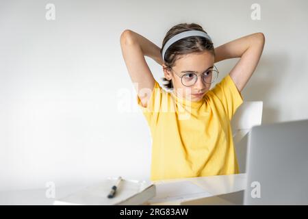 Süßes Schulmädchen mit einem Laptop, das zu Hause lernt, online lernt. Stockfoto
