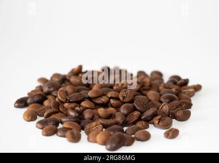 Kaffeebohnen. Gruppe brauner Kaffeebohnen auf der weißen Oberfläche. Isoliert auf weißem Hintergrund. Selektiver Fokus. Stockfoto