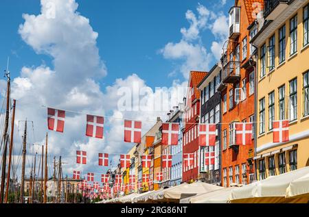Dänische Flaggen und farbenfrohe Gebäude in Nyhavn, Kopenhagen in Dänemark. Stockfoto