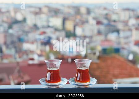 Zwei türkische Gläser in Form einer Tulpe gefüllt mit heißem schwarzem Tee mit Blick auf die Dächer des Uskudar-Viertels auf der asiatischen Seite von Istanbul, Türkei Stockfoto