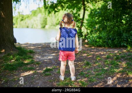 Ein bezauberndes Kleinkind, das im Park oder Wald spaziert. Ein Kind hat an einem Sommertag Spaß im Freien. Aktivitäten im Freien für Kinder Stockfoto