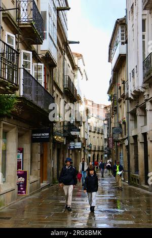 Touristen an einem nassen Juni-Tag in einer engen Fußgängerzone im historischen Stadtzentrum Santiago de Compostela Galicien Spanien Stockfoto