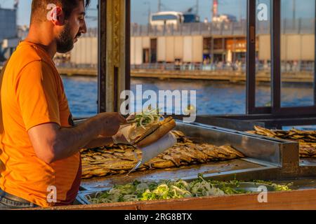 Istanbul, Türkei, Turkiye. Cook Frying Fish, Fisch Sandwiches für Boat-Side Restaurant an der Galata Bridge, Eminonu. Stockfoto