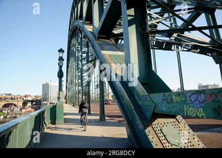 Die Tyne Bridge in Newcastle wurde offiziell zur George 5. Bridge ernannt. Gewölbte Brücke über den Fluss Tyne, die Newcastle und Gateshead verbindet. Radfahrer und Graffiti. Stockfoto