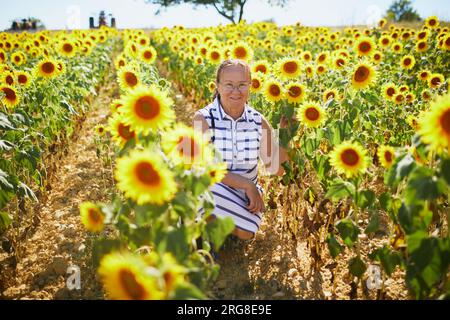 Seniorin auf einem Feld mit Sonnenblumen in der Provence, Frankreich Stockfoto