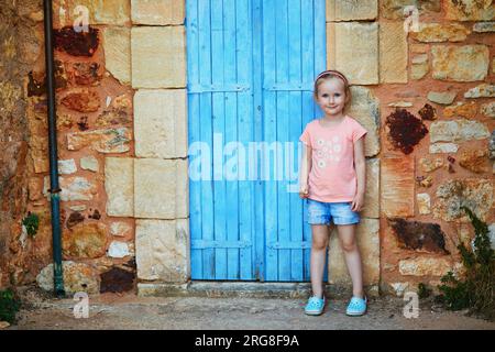 Fröhliches Vorschulmädchen, das Spaß an der Backsteinmauer in Roussillon, Provence, Südfrankreich hat Stockfoto