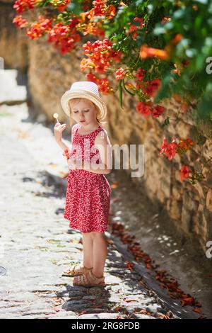 Bezauberndes Vorschulmädchen, das auf einer Straße des mittelalterlichen Dorfes Gordes in der Provence, Südfrankreich, spaziert Stockfoto