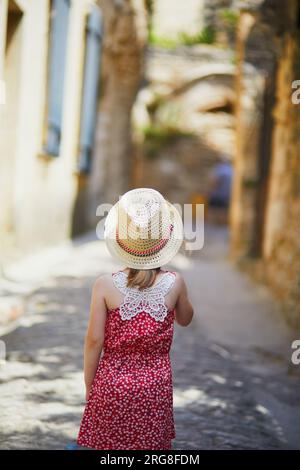 Bezauberndes Vorschulmädchen, das auf einer Straße des mittelalterlichen Dorfes Gordes in der Provence, Südfrankreich, spaziert Stockfoto