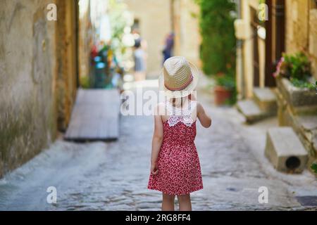 Bezauberndes Vorschulmädchen, das auf einer Straße des mittelalterlichen Dorfes Gordes in der Provence, Südfrankreich, spaziert Stockfoto