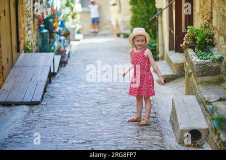 Bezauberndes Vorschulmädchen, das auf einer Straße des mittelalterlichen Dorfes Gordes in der Provence, Südfrankreich, spaziert Stockfoto