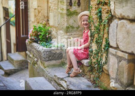 Bezauberndes Vorschulmädchen, das auf einer Straße des mittelalterlichen Dorfes Gordes in der Provence, Südfrankreich, spaziert Stockfoto