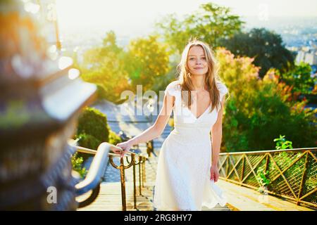 Wunderschöne junge Frau in weißem Kleid, die am frühen Morgen auf dem berühmten Montmartre-Hügel in Paris, Frankreich, spaziert Stockfoto