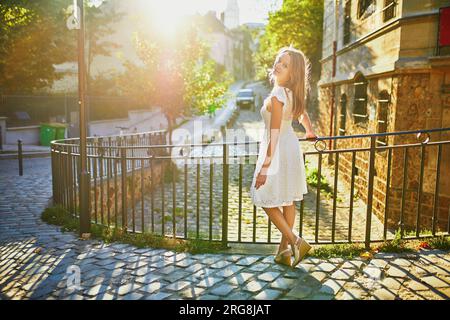 Wunderschöne junge Frau in weißem Kleid, die am frühen Morgen auf dem berühmten Montmartre-Hügel in Paris, Frankreich, spaziert Stockfoto