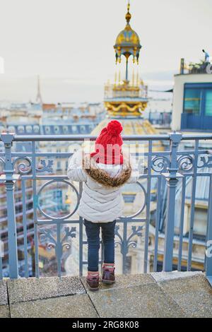 Bezauberndes kleines Mädchen mit Blick auf die Pariser Skyline mit Dächern und den Eiffelturm Stockfoto