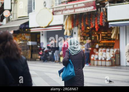 Eine nicht wiedererkennbare türkische Frau mit Kopfbedeckung, die auf einem Straßenmarkt im Uskudar-Viertel auf der asiatischen Seite von Istanbul, Türkei, einkaufen geht Stockfoto