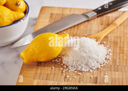 Zitrone und Haufen grobes Meersalz auf dem Schneidebrett Stockfoto