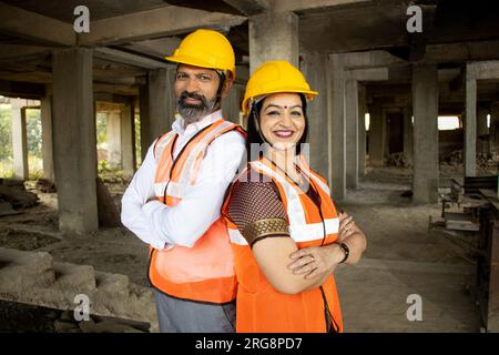 Porträt von zwei indischen Bauingenieuren oder Architekten, die einen Helm tragen, der mit Querarmen steht. Immobilien. Stockfoto