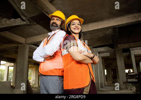 Porträt von zwei indischen Bauingenieuren oder Architekten, die einen Helm tragen, der mit Querarmen steht. Immobilien. Stockfoto