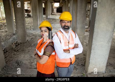 Porträt von zwei indischen Bauingenieuren oder Architekten, die einen Helm tragen, der mit Querarmen steht. Immobilien. Oberer Winkel Stockfoto