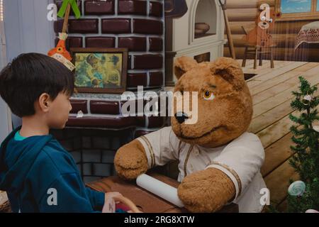 Der Junge schaut auf den Koch-Bären Stockfoto