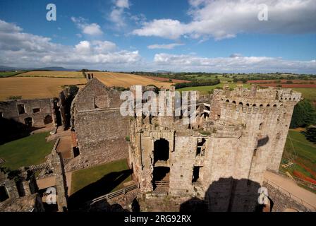 Raglan Castle in der Nähe von Raglan, Gwent, eine Militärfestung, die im Mittelalter erbaut wurde, um die walisische Grenze gegen die Engländer zu verteidigen. Es wurde eine Ruine während des Englischen Bürgerkriegs. In den letzten Jahren war es als Film- und Fernsehstandort sehr beliebt. Eine Luftaufnahme mit Feldern im Hintergrund. Stockfoto