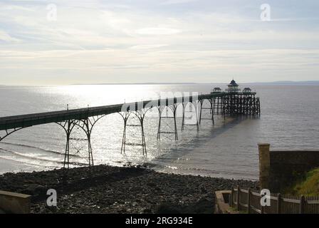 Blick auf den Pier im Badeort Clevedon in der Grafschaft Avon, mit der Sonne, die auf das Meer scheint. Der Pier wurde 1869 eröffnet. Seitdem wurden zahlreiche Reparatur- und Restaurierungsarbeiten durchgeführt, und der Pier ist nun ein Gebäude der Kategorie I. Stockfoto