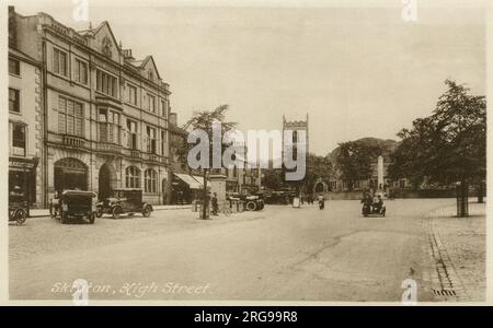 Blick auf die High Street, Skipton, North Yorkshire, mit der freien Bibliothek auf der linken Seite und dem Kriegsdenkmal und der Kirche der Heiligen Dreifaltigkeit in der Ferne. Stockfoto