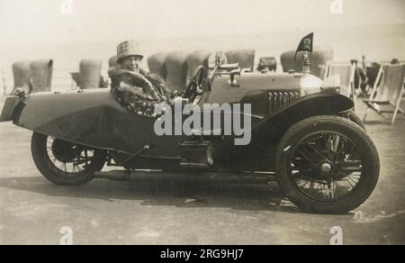 Jolly Woman, die für ein Foto posiert, sitzt in einem fabelhaften 1927 Morgan Aero 1100cc dreirädrigen Auto an der Küste in Margate, Kent. Stockfoto