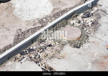 Straße und Bürgersteig sind voller Löcher. Straßenreparatur. Beseitigen Sie Unebenheiten und Löcher auf der Straße. Hintergrund. Draufsicht der Umgebung. Stockfoto