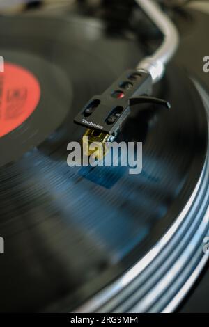 Close up Vinyl record playing spinning on Technics 1210 MK2 DJ Deck turntable with motion blur. Stock Photo