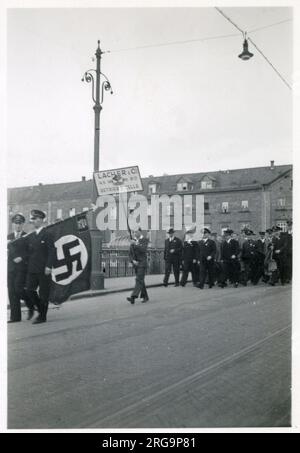 Rallye - Parade - Pforzheim, Südwestdeutschland am 1. Mai 1935. Unter der Flagge der Nazis stehen Arbeiter von LACO (Lacher & Co), die im Jahr WW2 Uhren für deutsche Airforce-Piloten und Beobachter von Bombenflugzeugen herstellten. Stockfoto