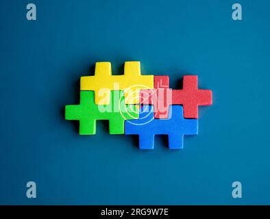 Vier Puzzleblöcke in verschiedenen Farben sind perfekt mit dem Zielsymbol auf blauem Hintergrund, minimalistisch, zusammengestellt. Geschäftspartner, Teamgeist Stockfoto