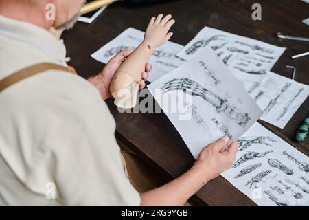 Nahaufnahme eines Handwerkers, der sich detaillierte Pläne und Entwürfe von Prothesen in Werkstatt, Kopierraum ansieht Stockfoto