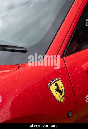 Das Seitenlogo und die Windschutzscheibe eines roten italienischen Ferrari F8 Tributo Sportwagens im Hochformat zeigen das „Prancing Horse“-Logo. Stockfoto