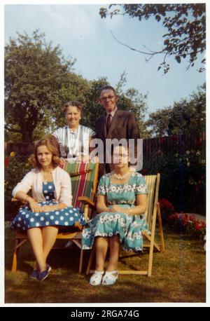 Eine Familiengruppe von Mutter, Tochter, Onkel und Tante - im Garten / Liegestühle in einem eleganten Vorstadtgarten im späten Abendlicht - September 1959 Stockfoto