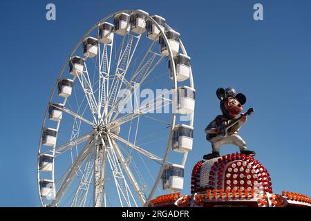 Modernes Riesenrad mit geschlossenen Kabinen auf dem Karneval mit blauem Himmel, keine Wolken im Hintergrund, beleuchtete Weitwinkel-Nahaufnahme Stockfoto