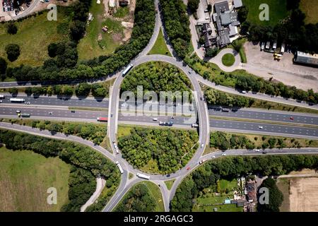 Luftaufnahme direkt über einer geschäftigen Straßenkreuzung auf einer britischen Autobahn mit Überbrückung und Zufahrtsstraßen in der britischen Landschaft Stockfoto