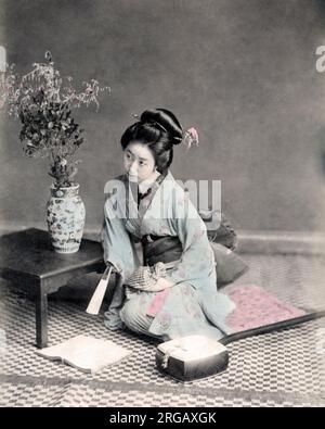 Geisha mit einem Fan, der ein Buch liest, Japan, c.1880s Vintage Foto aus dem späten 19.. Jahrhundert Stockfoto