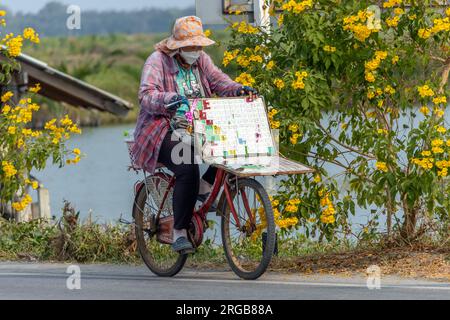 SAMUT PRAKAN, THAILAND, MÄRZ 09 2023, Eine Lotterieverkäuferin fährt Fahrrad Stockfoto