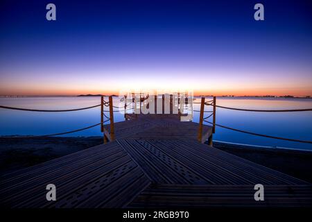 Holzsteg am Strand von Punta Brava bei einem warmen Sonnenaufgang in Cartagena, Region Murcia, Spanien Stockfoto