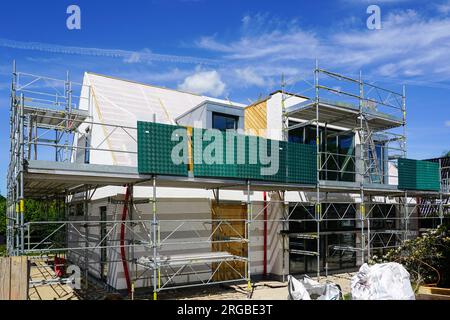 Ein unvollendetes modernes Einfamilienhaus, umgeben von Gerüsten, blauer Himmel Hintergrund, Wohnhaus im Bau Stockfoto