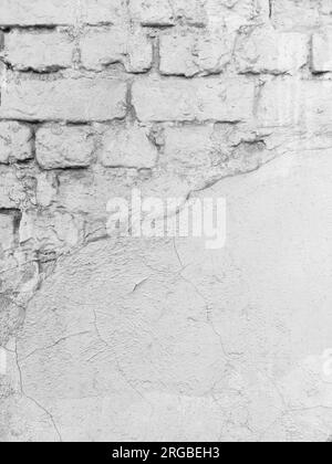 Oberfläche der verputzten Ziegelwand des alten Gebäudes mit Rissen und abbröckelndem Putz als Hintergrund. Speicherplatz kopieren. Schwarzweißfoto. Selektiver Fokus. Stockfoto